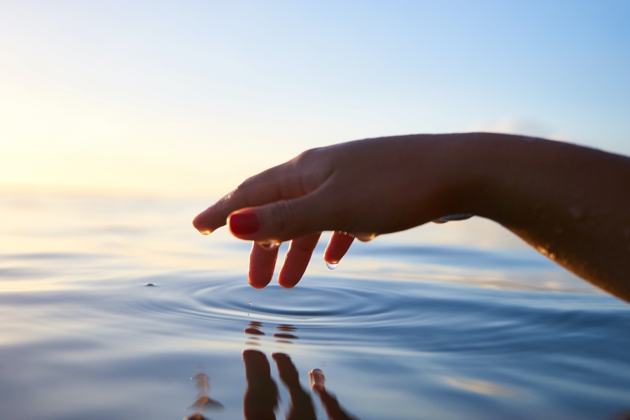 Person about to touch water (Bild: Yoann Boyer auf Unsplash)